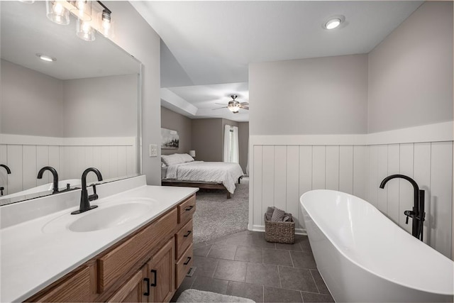 ensuite bathroom with vanity, wainscoting, ceiling fan, and a freestanding bath