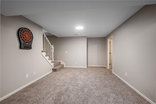 finished below grade area featuring carpet floors, baseboards, and stairway