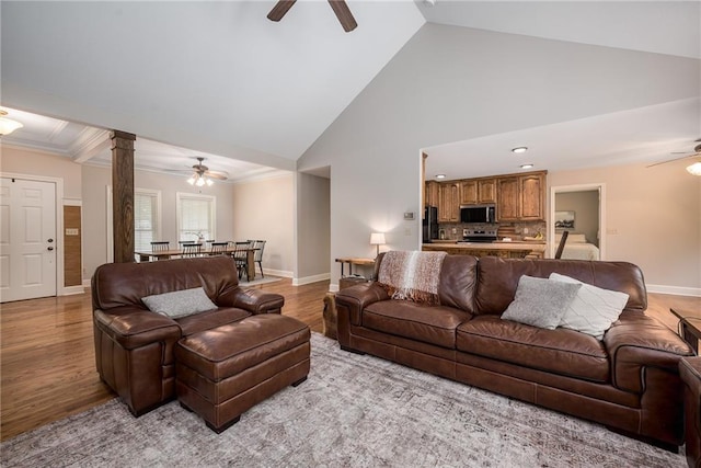 living room featuring baseboards, a ceiling fan, light wood finished floors, and high vaulted ceiling