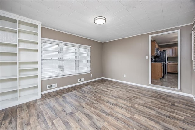 306 S 5th St, Neodesha, KS 66757 - unfurnished living room featuring wood finished floors, visible vents, ornamental molding, and baseboards