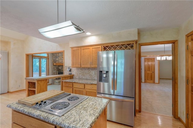 12341 Beverly St, Leawood, KS 66209 - kitchen featuring appliances with stainless steel finishes, tasteful backsplash, light stone counters, baseboards, and a textured ceiling