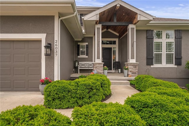 property entrance with covered porch, an attached garage, concrete driveway, and stucco siding