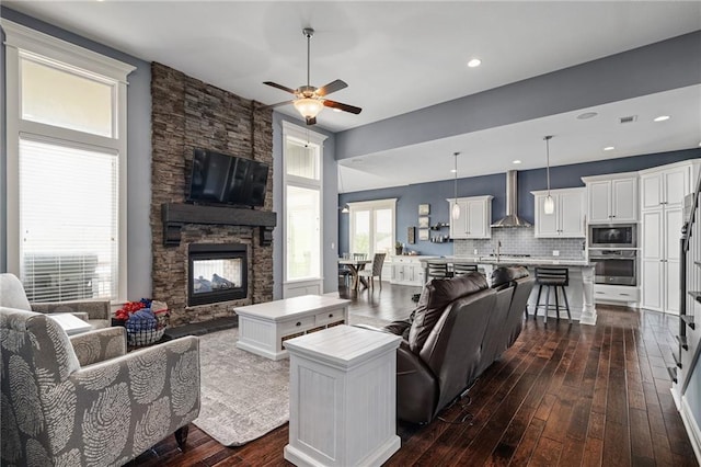 living room with recessed lighting, ceiling fan, dark wood-style floors, and a fireplace