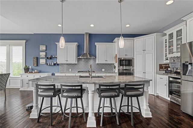 kitchen featuring wall chimney range hood, stainless steel appliances, beverage cooler, and white cabinetry