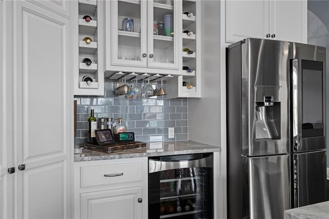 interior space with white cabinets, wine cooler, backsplash, stainless steel refrigerator with ice dispenser, and glass insert cabinets