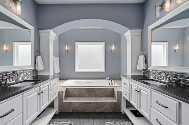 full bathroom with a sink, decorative backsplash, and decorative columns