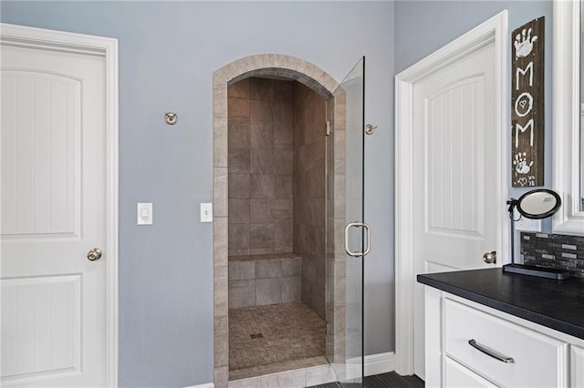 bathroom featuring vanity, baseboards, and a stall shower