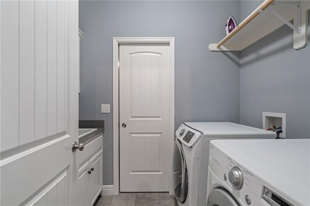 laundry room with cabinet space, light tile patterned floors, and washer and dryer
