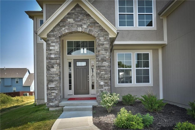doorway to property featuring stucco siding and stone siding