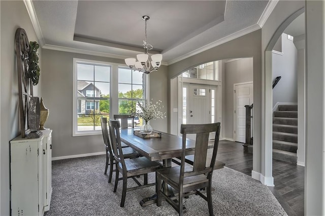 dining space featuring a chandelier, a raised ceiling, stairs, and ornamental molding