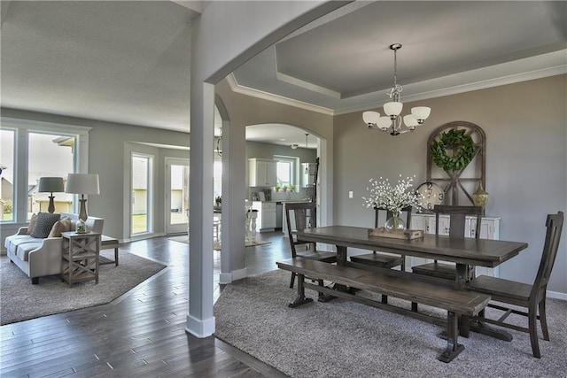 dining area with crown molding, arched walkways, an inviting chandelier, baseboards, and dark wood-style flooring
