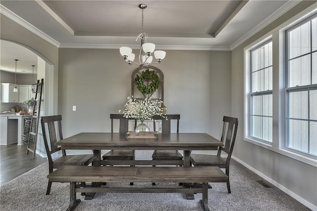 dining space with arched walkways, a raised ceiling, baseboards, and an inviting chandelier