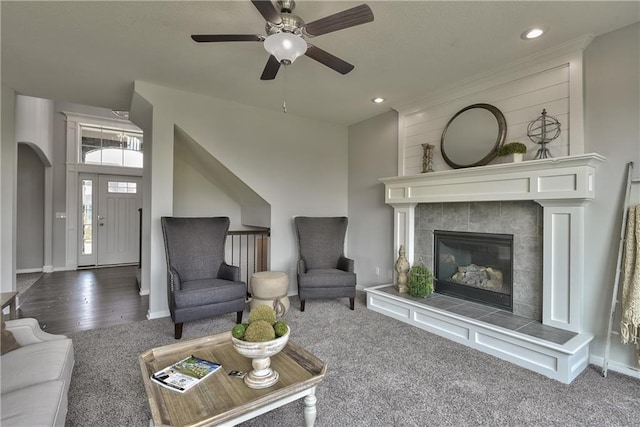 living area with a ceiling fan, arched walkways, a tiled fireplace, baseboards, and recessed lighting
