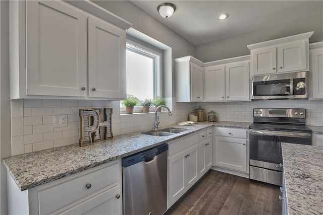kitchen with a sink, white cabinetry, appliances with stainless steel finishes, and dark wood-style flooring