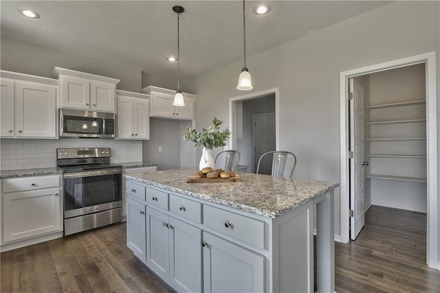 kitchen featuring dark wood-style flooring, appliances with stainless steel finishes, white cabinetry, and a kitchen island