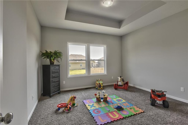 rec room featuring a raised ceiling, carpet, and baseboards