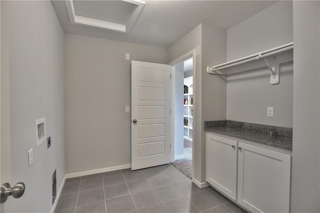 laundry area with visible vents, baseboards, dark tile patterned flooring, electric dryer hookup, and a textured ceiling
