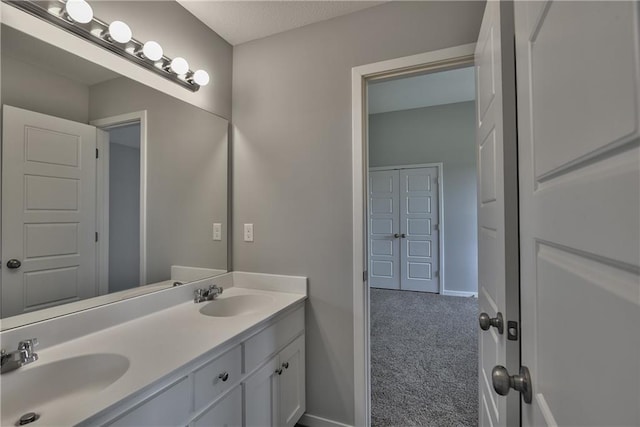 bathroom featuring baseboards, a sink, and double vanity