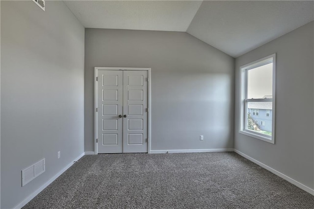 carpeted empty room with lofted ceiling, visible vents, and baseboards