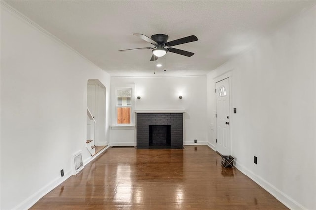 unfurnished living room featuring ceiling fan, visible vents, a brick fireplace, wood finished floors, and baseboards