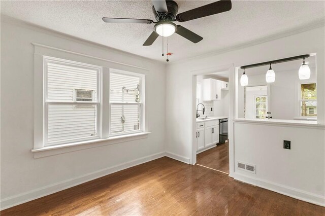 empty room featuring visible vents, baseboards, ceiling fan, a sink, and dark wood finished floors