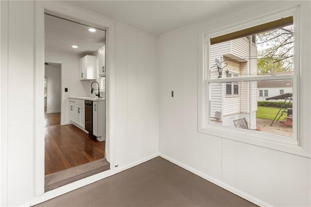 empty room featuring baseboards, a sink, crown molding, and recessed lighting