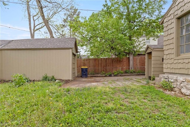view of yard with fence, a storage unit, and an outbuilding