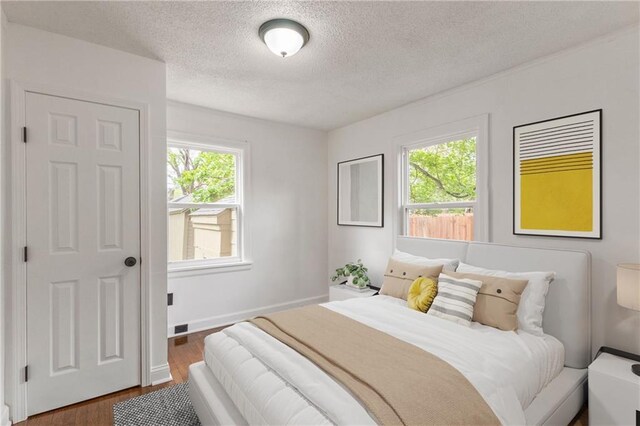 1133 E 75th St, Kansas City, MO 64131 - bedroom featuring multiple windows, wood finished floors, a textured ceiling, and baseboards