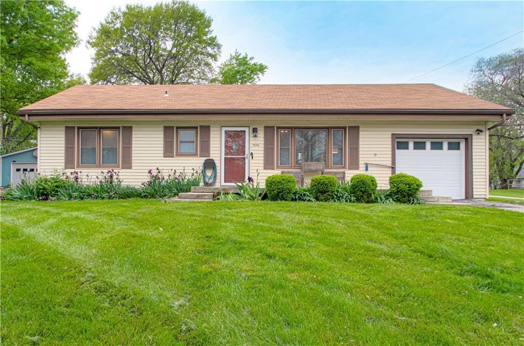 ranch-style home featuring a shingled roof, an attached garage, driveway, and a front yard