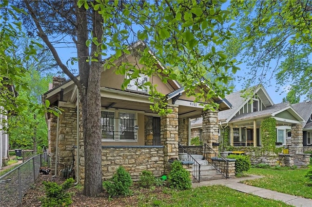 craftsman-style house featuring fence, a porch, and stone siding