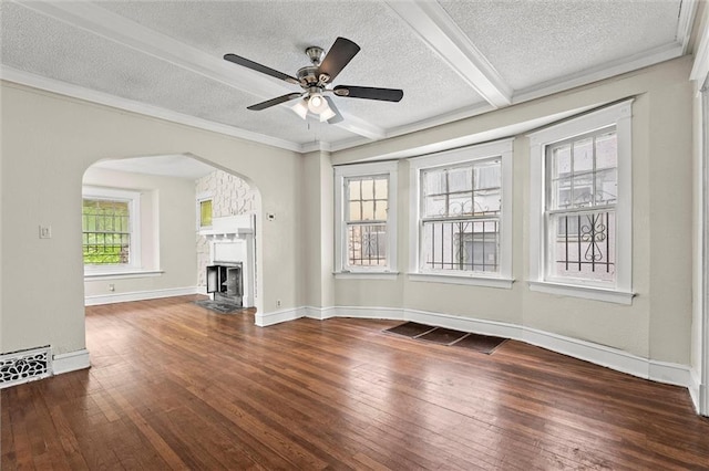 unfurnished living room featuring wood-type flooring, arched walkways, a textured ceiling, and a fireplace with flush hearth