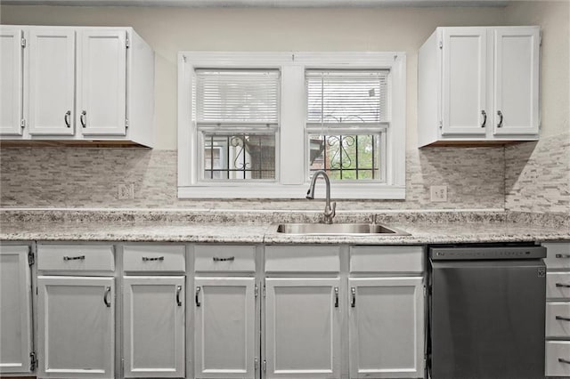 kitchen with stainless steel dishwasher, white cabinetry, a sink, and backsplash