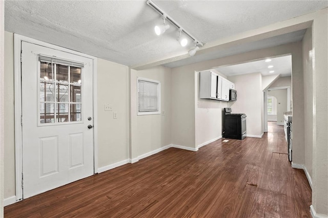 foyer entrance featuring baseboards, a textured ceiling, dark wood finished floors, and track lighting