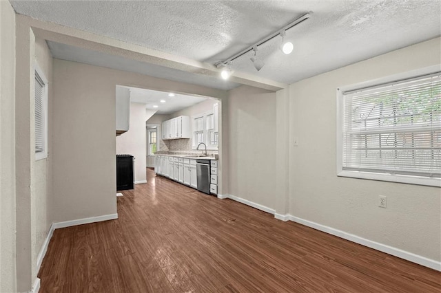kitchen featuring dark wood-style flooring, track lighting, dishwasher, white cabinetry, and baseboards