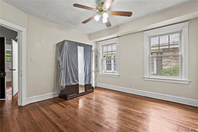 spare room featuring wood-type flooring, a ceiling fan, baseboards, and a textured ceiling