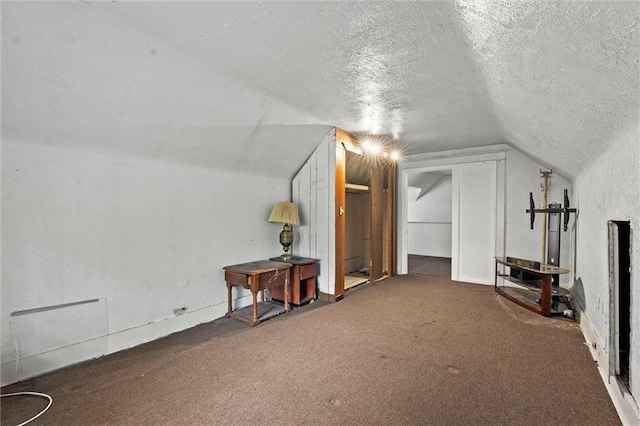 additional living space with carpet floors, a textured ceiling, a textured wall, and lofted ceiling