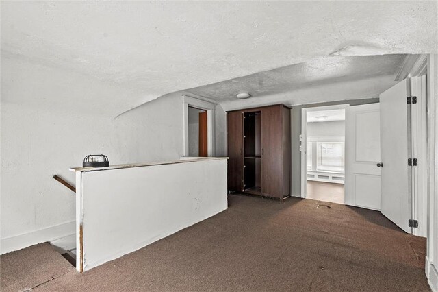 interior space with dark colored carpet and a textured ceiling