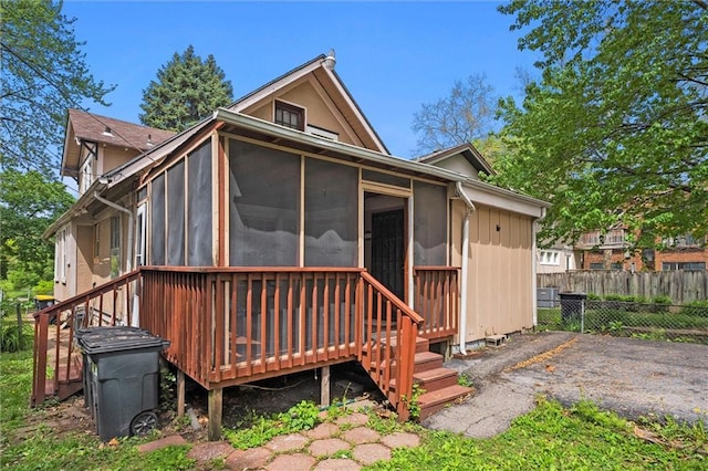 back of property featuring fence, a sunroom, and a deck