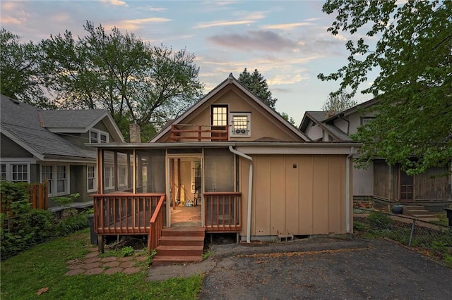rear view of house featuring a sunroom and a deck