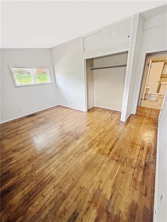 unfurnished bedroom featuring baseboards, a closet, light wood-type flooring, and visible vents