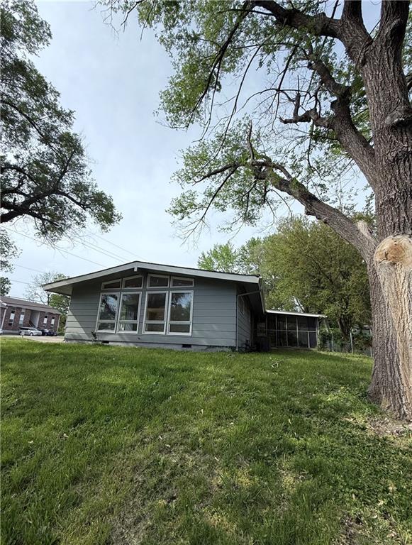 rear view of property with a lawn and a sunroom