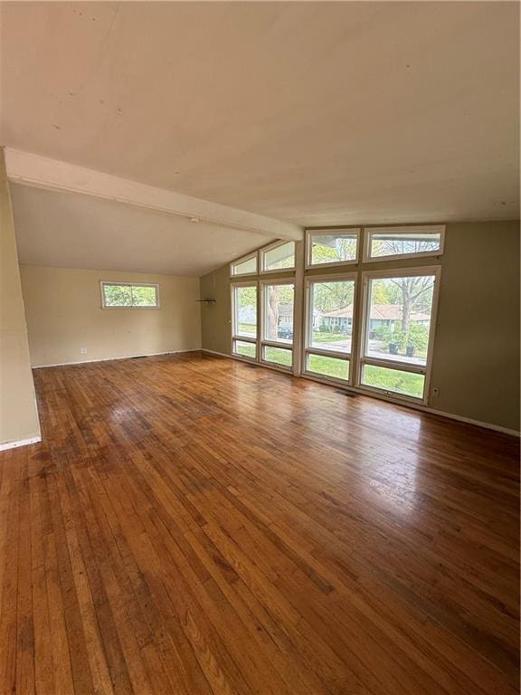 unfurnished room with baseboards, vaulted ceiling with beams, and hardwood / wood-style flooring