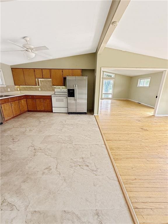 kitchen with brown cabinets, white range with electric stovetop, lofted ceiling with beams, and stainless steel fridge