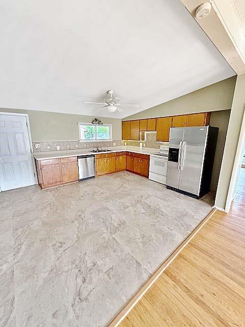 kitchen with decorative backsplash, ceiling fan, brown cabinets, a sink, and appliances with stainless steel finishes