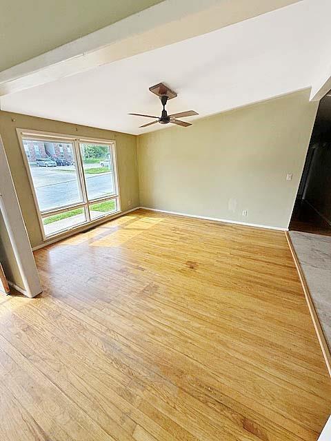 spare room with baseboards, a ceiling fan, and light wood finished floors