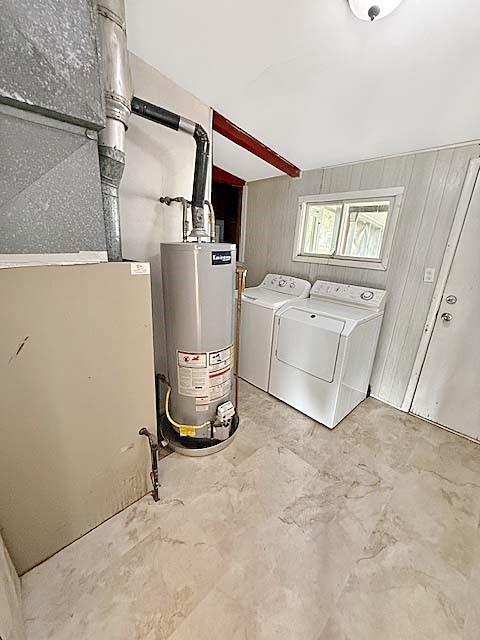 laundry room with laundry area, heating unit, washing machine and dryer, and gas water heater