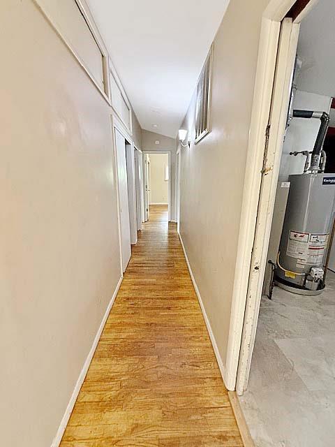 hallway with baseboards and water heater