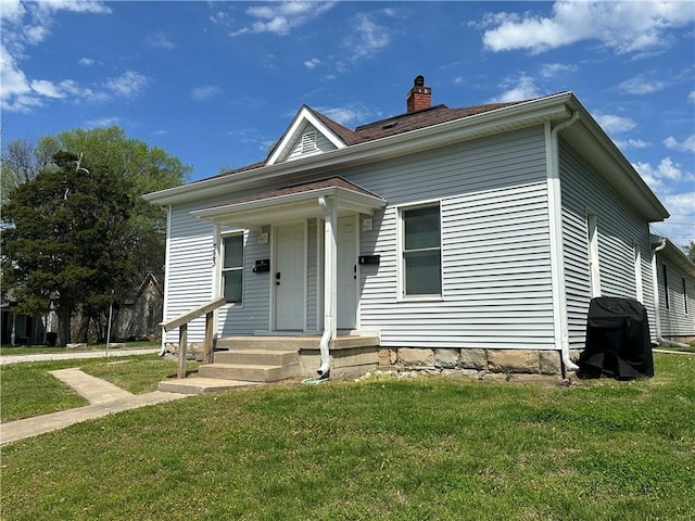 bungalow-style house featuring a front lawn and a chimney