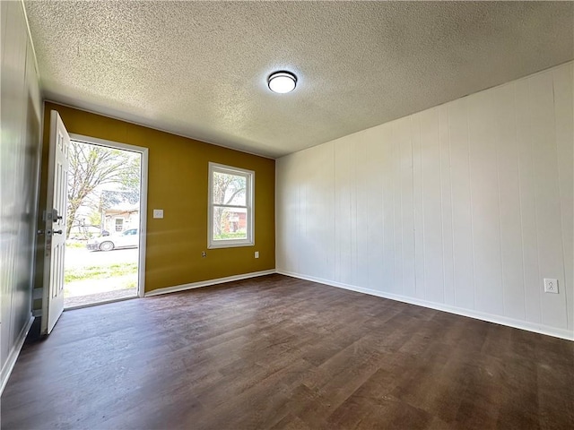 empty room with baseboards, dark wood-type flooring, and a textured ceiling