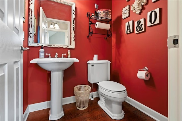 bathroom with a sink, toilet, wood finished floors, and baseboards